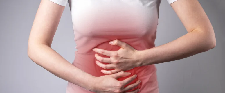 Woman holding her stomach in pain due to ulcerative colitis symptoms including cramping and abdominal discomfort